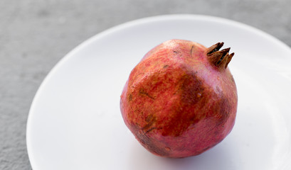 Fresh raw ripe pomegranate on a white plate, close up view, fruit, background