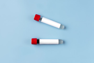 Two vacuum blood test tubes with a blank label for inserting text on a blue background. The concept of a coronavirus or covid-19