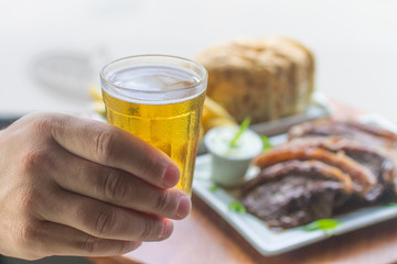 Mão segurando copo de cerveja
