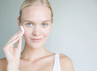 Blonde woman using cotton pad on her face. Beautiful model using cotton pad. Healthy woman using treatment on her face. 