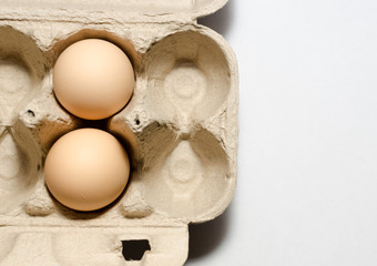 Fototapeta na wymiar white and beige eggs in a cardboard box on a light background