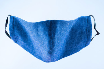 Face protective mask. Antivirus mask made from denim. Blue denim face mask during a pandemic virus COVID-19. Protective mask on a blue background