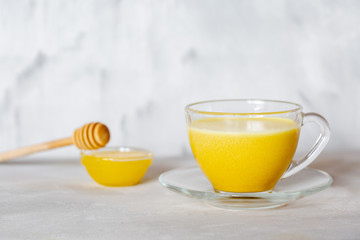 Obraz na płótnie Canvas Golden milk in a glass mug on a gray background. Healthy drink from india.