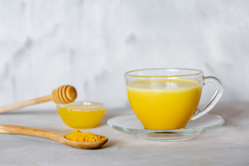 Golden milk in a glass mug on a gray background. Healthy drink from india.