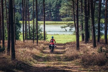 Woman rides bicycle in forest near Lizaki, small village located in Kaszuby region, Poland