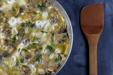 Mushroom meal in a pan, wooden spoon on the skin