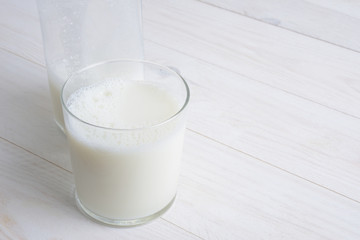 Vaso de leche y botella con tapón en la mesa blanca