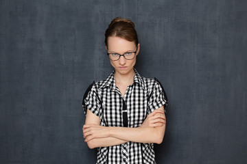 Portrait of angry enraged girl with glasses, crossing arms over body