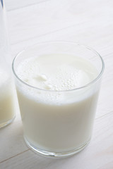 Vaso de leche y botella con tapón en la mesa blanca