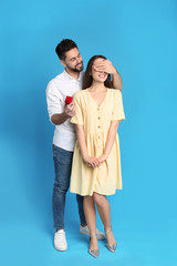 Man with engagement ring making marriage proposal to girlfriend on blue background
