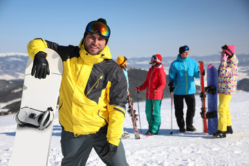 Young man with snowboard at ski resort. Winter vacation