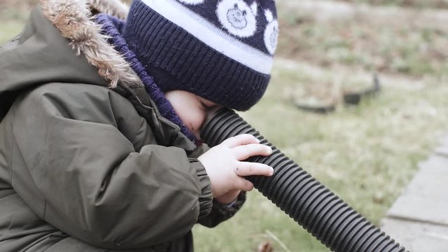 Boy in overalls plays with a corrugated