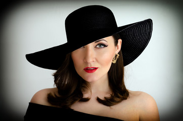 Portrait of a female model in a black hat on a white background
