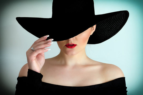 Portrait of a female model in a black hat on a white background