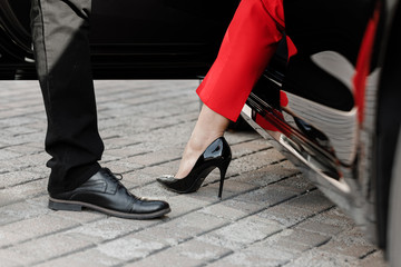 Close up image of a business woman getting out of her car with high heels shoes.