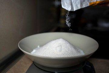 Pouring sugar into a deep plate. Close-up.