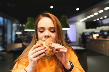 Closeup portrait of pretty lady biting burger with her eyes closed and having fun. Pretty girl...