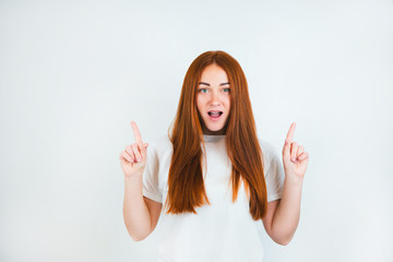 portrait of redheaded young woman looking natural standing on isolated white backgroung pointing...