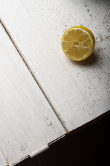 Yellow lemons in a black bowl, on a white wooden table.