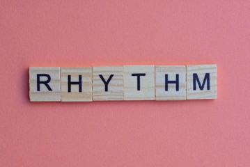 short small lettering rhythm in gray wooden letters with black font on a pink table