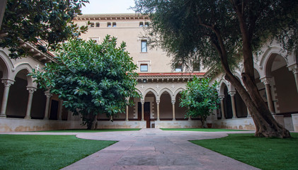 Fototapeta na wymiar Courtyard in a cloister in Barcelona with trees and an elegant arch.