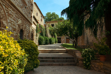 Fototapeta na wymiar Cozy medieval courtyard with stone buildings and green plants.