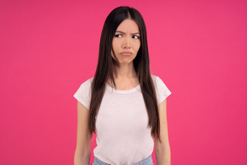 Gloomy sad Asian woman has unhappy look, expresses regret and sadness, frowns face, being...
