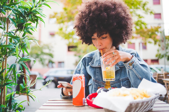 Young woman with afro hairdo at an outdoor cafe in the city