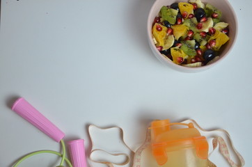 Fitness, healthy fruits, Fresh healthy salad, diet and active lifestyles Concept, dumbbells, fresh fruits, bottle for water, measure centimeter, jump rope on a white background . copy space for text.