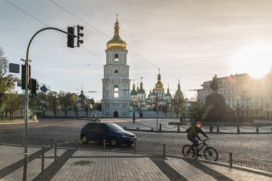 Rare car and biker passing empty Sofyivska Square with Saint Sophia Cathedral and Bohdan Kmelnitsky monument during covid-19 quarantine in the center of Kyiv, Ukraine.