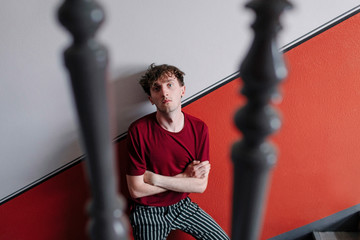 Portrait of serious young man leaning against wall