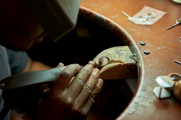 Man repairing a ring with a missing diamond