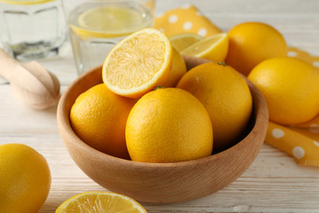 Bowl with fresh lemons on wooden background, close up