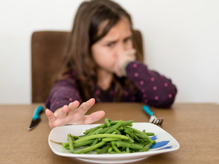 Enfant repoussant son assiette de haricots verts