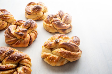 Fresh baked cinnamon buns on white table. Bakery and food photography concept.