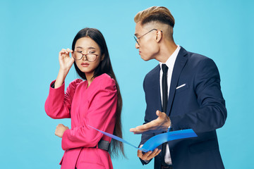 Cheerful young couple of Asian appearance officials elegant office style