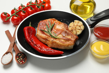 Pan with fried steaks and ingredients for cooking on white background, close up