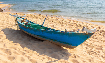 Abandoned fishing boat on the sandy seashore. Old wooden boat on tropical beach.