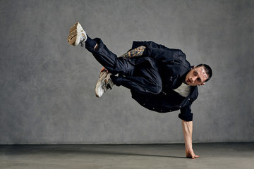 Active man with tattooed body, beard. Dressed in white t-shirt and sneakers, black shirt, pants....