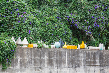 Garten und Gartengestaltung: Dekoration einer Mauer mit Keramik Vasen und Gefäßen mit üppig...