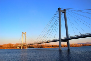 Fototapeta na wymiar Sunset view of the foot Vinogradovsky (cable-stayed) bridge through the Yenisei river on Tatyshev island in Krasnoyarsk, Russia