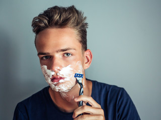 Cute handsome young man, teenager shaves first time, concept