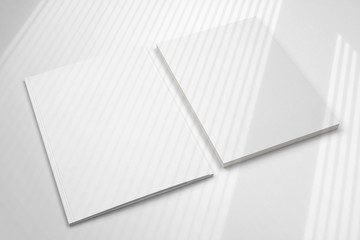 Blank folder and letterheads stack on white desk with shadow overlay as template for design, logo...