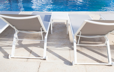 Fototapeta na wymiar Vacant white sunloungers by a pool