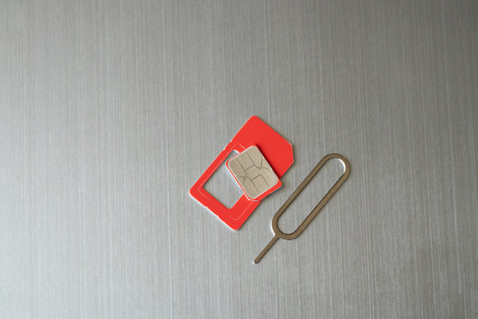 a sim card and a paper clip for opening a slot for a sim card lies on a gray steel background close-up