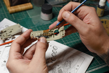 Plastic Modeling and model building. Close up of male hands painting and assembling scale model of...