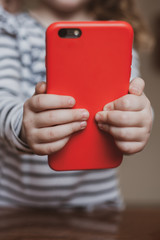 Cute girl holding a red mobile phone in her hands