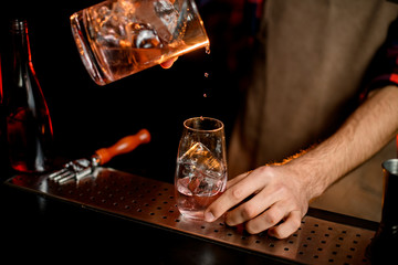 Close-up of barman gently pouring drink into glass.