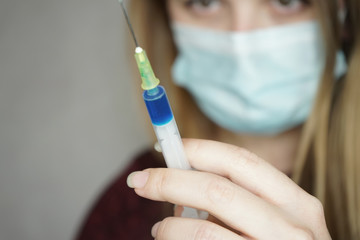 Young woman wearing a face mask and hold a vaccine