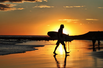 Surfer and his board with beautiful sunset